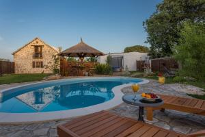 a swimming pool in a yard with a table and a drink at Kuća za odmor Joko i Jeka in Bogatić