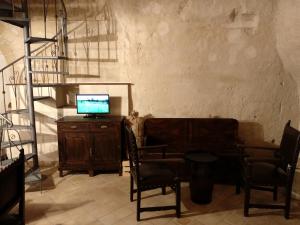 uma sala de estar com uma secretária, uma televisão e cadeiras em Casa Masiello La casa tipica dei Sassi di Matera em Matera