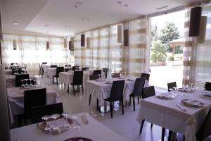 a restaurant with white tables and chairs and a large window at Virginia Palace Hotel in Garbagnate Milanese