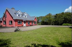 una gran casa roja con un gran patio en BlueTit Lodge en Kilkee