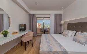 Pokój hotelowy z łóżkiem, biurkiem i telewizorem w obiekcie Oscar Hotel w Laganas