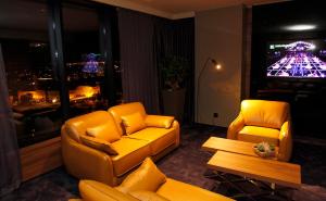 a living room with two yellow chairs and a tv at Ambasador Hotel in Niš