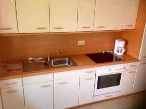 eine Küche mit weißen Schränken, einer Spüle und einer Mikrowelle in der Unterkunft Haus Weserbergland in Porta Westfalica