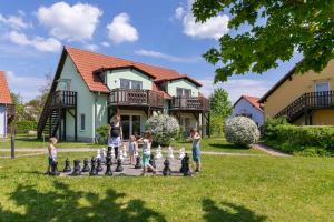 eine Gruppe von Kindern, die Schach auf einem Schachbrett vor einem Haus spielen in der Unterkunft Feriendorf Alte Fahrt in Rechlin