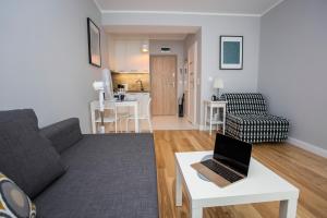 CR Wygodny Apartament w Centrum Nowy Świat 13 في بياويستوك: غرفة معيشة مع أريكة وجهاز كمبيوتر محمول على طاولة +33 صورة