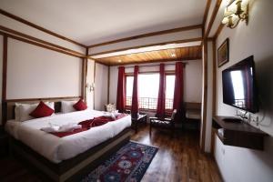 een slaapkamer met een groot bed en een televisie bij Buddha Retreat in Ravangla