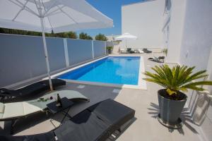 - une piscine avec des chaises et un parasol sur la terrasse dans l'établissement Hotel Paradise Punta, à Nečujam