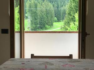 a bedroom with a window with a view of a forest at Appartamenti Rì de Clama in Andalo