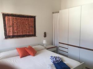 ein Schlafzimmer mit einem weißen Bett mit orangefarbenen und blauen Kissen in der Unterkunft Apartment Sillemi - Casa Sille in Letojanni