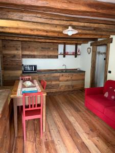 a kitchen with a wooden table and a red couch at La Tzambretta in Aosta