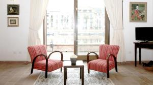 a living room with two chairs and a table and a television at Bosa Exclusive Apartments "Bosa Apartments" in Bosa