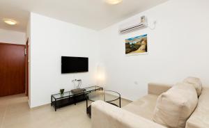 a living room with a couch and a tv on a wall at Home4Trip Bat Yam in Bat Yam