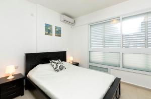 a bedroom with a bed and two windows at Home4Trip Bat Yam in Bat Yam