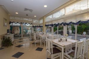 a restaurant with white tables and chairs and windows at Семеен хотел Бриз in Sozopol
