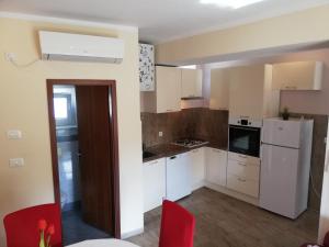 a small kitchen with white cabinets and red chairs at Apartment Luka in Mali Lošinj