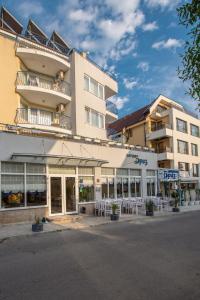 a large building with tables and chairs in front of it at Семеен хотел Бриз in Sozopol