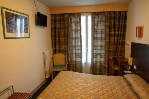 a bedroom with a bed and a table and a desk at Hôtel Sainte Suzanne in Lourdes