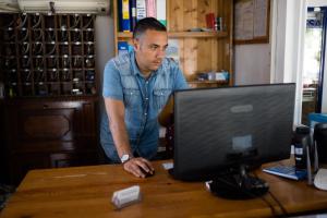 a man sitting at a desk with a computer at Hotel Santa Rosalia in Marina di Camerota