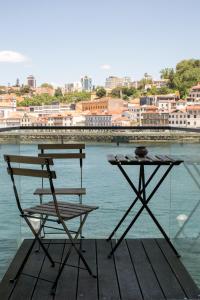 une table et une chaise assises sur un quai à côté de l'eau dans l'établissement Douro triplex - Destilaria Residence by Porto City Hosts, à Vila Nova de Gaia