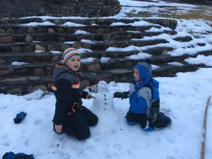 Departamentos Exclusivos Termas de Chillán في Nevados de Chillan: طفلين يلعبون بالثلج مع رجل ثلج