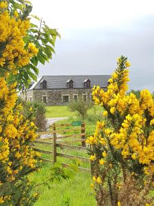 a fence in front of a house with yellow flowers at Heathfield Highland Estate in Invergordon