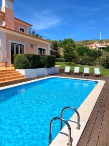 a swimming pool with chairs next to a house at Villa with swimming pool in Golf Resort in Torres Vedras