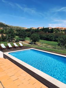 a swimming pool with chairs and a view of a house at Villa with swimming pool in Golf Resort in Torres Vedras