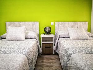2 Betten in einem Zimmer mit grüner Wand in der Unterkunft Apartamentos Cocó in Avila