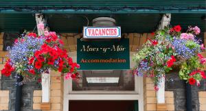 ein Schild auf einem Gebäude mit Blumen darauf in der Unterkunft Rooms by Maes y mor Town Centre in Aberystwyth