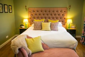 ein Schlafzimmer mit einem großen Bett mit gelben Kissen in der Unterkunft Leeds Castle Stable Courtyard Bed and Breakfast in Maidstone