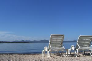 dos sillas sentadas en una playa junto al agua en Rooms & Apartments Linda & Mario, en Zadar