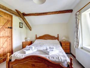 a bedroom with a wooden bed with two pillows at Holiday Home Nythfa by Interhome in Llanycrwys