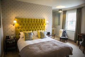 1 dormitorio con 1 cama grande y cabecero amarillo en Leeds Castle Stable Courtyard Bed and Breakfast en Maidstone
