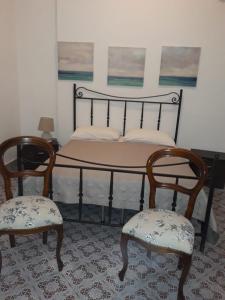 a bedroom with a bed with two chairs and a bed with two posters at Mazzarò Isola Bella in Taormina