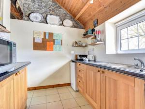 a kitchen with wooden cabinets and a sink at Holiday Home Nythfa by Interhome in Llanycrwys