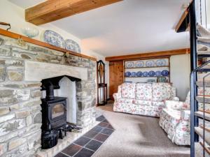 a living room with a stone fireplace and a couch at Holiday Home Nythfa by Interhome in Llanycrwys