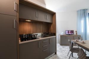 a kitchen with brown cabinets and a table and a dining room at Residence Gambrinus in Giulianova