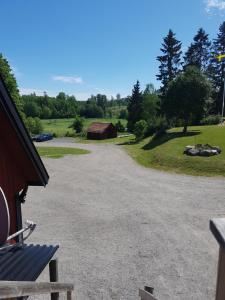 a gravel driveway with a barn and a bench at Rialahästgård in Uddeby