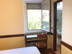 a bedroom with a window with a chair and a table at Hotel Signa in Perugia