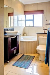 een badkamer met een bad, een wastafel en een toilet bij 9 Seesonnet Scottburgh in Scottburgh