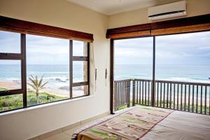 a bedroom with a balcony with a view of the ocean at 9 Seesonnet Scottburgh in Scottburgh