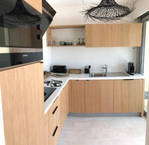 a kitchen with wooden cabinets and a stove top oven at JACARANDA II Appartement in Mandelieu-La Napoule +27 photos