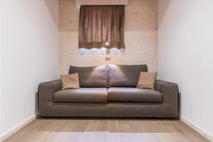 a brown couch in a room with a window at Hotel La Sorgente in Tesero