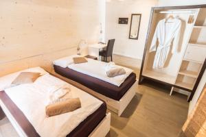 two beds in a room with a desk and a mirror at Hotel La Sorgente in Tesero