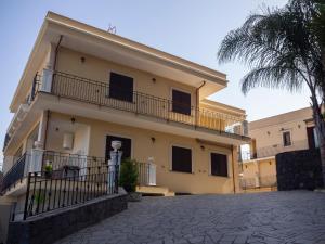 a yellow building with a balcony and a palm tree at Viaggio in Sicilia B&B in Gravina di Catania