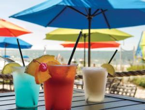 três bebidas sentadas numa mesa com um guarda-chuva em Diamond Head Beach Resort em Fort Myers Beach