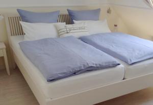 a white bed with blue sheets and pillows at Haus Südwind in Büsum