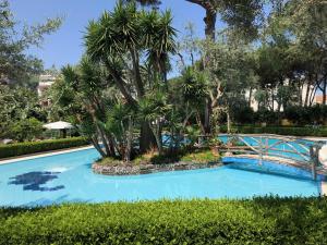 a blue swimming pool with a bridge and trees at Casa Bice Amazing view of Vesuvius in Sorrento