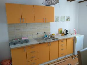 a kitchen with wooden cabinets and a sink and a refrigerator at Apartments Aida in Bihać