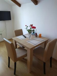 a wooden table with chairs and a vase of flowers on it at Apartments Aida in Bihać